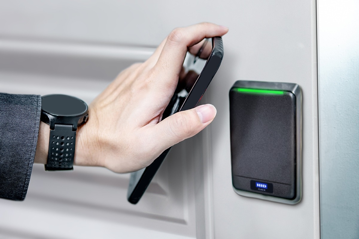 Close up of person's hand using their smartphone as a fob to open an apartment door