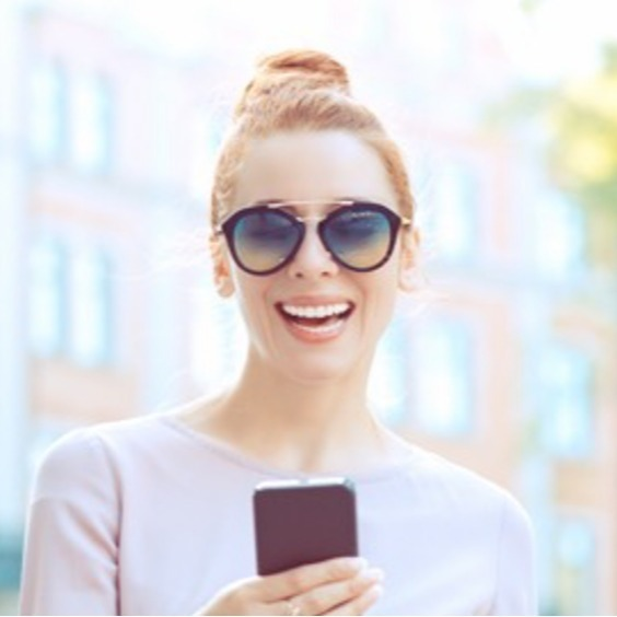 Happy woman wearing sunglasses using self-guided tour app